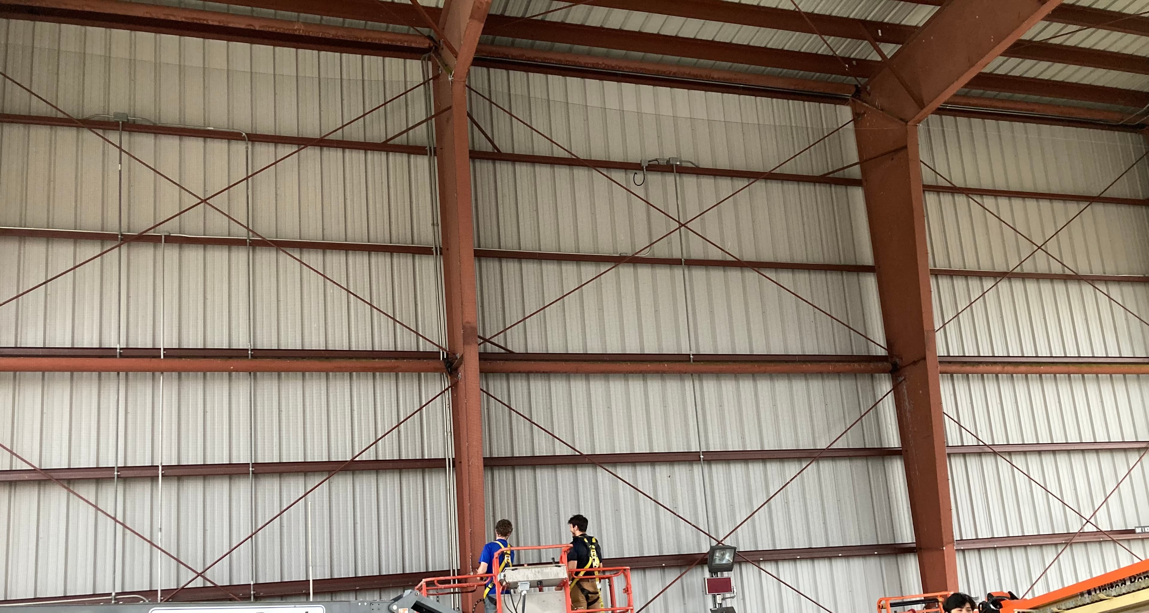 Technicians installing bird netting on industrial metal framework
